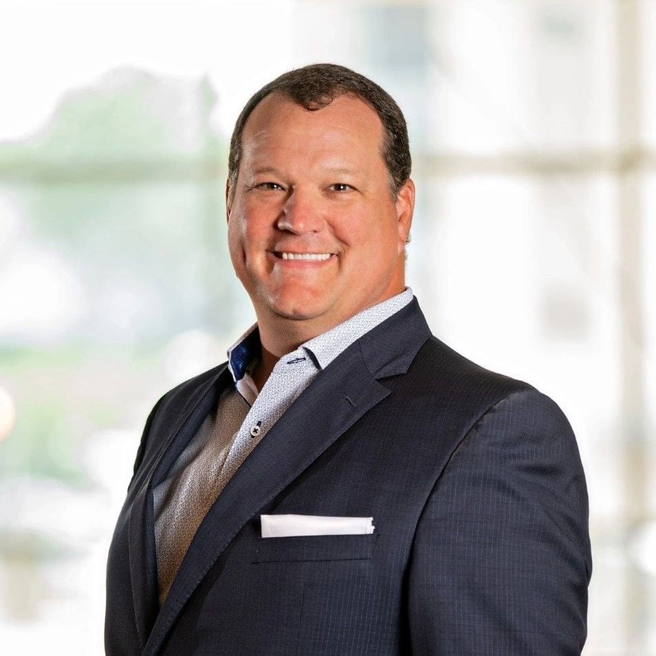 A man in a suit and tie smiling for the camera.